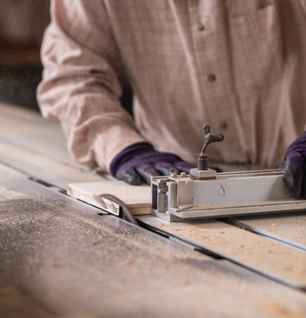 Manual worker using circular saw machine in carpentry workshop